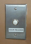 wall-mounted button with label reading 'door release'