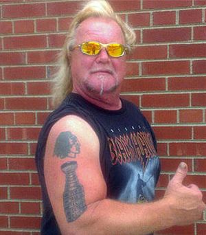 A man wearing sunglasses gives a hearty thumbs up to his Stanley Cup tattoo that features the Chicago Blackhawks as the 2013 winners before they had won.