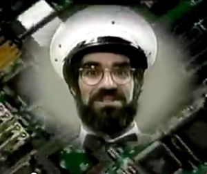The face, hat and bow tie of the self-declared COMPUTER MAN appears in a circular cloud over a background image of a computer's circuit board.