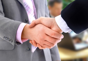 A close-up of a handshake by two men in business clothes.