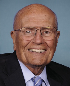 Official portrait of Rep. John Dingell, D-Mich., posing in suit in front of blue background
