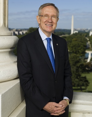 Image greying bespectacled Sen. Harry Reid, wearing dark suit, white shirt and blue patterned tie, with Washington Monument visible over his shoulder