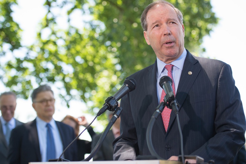 Sen. Tom Udall speaking at a podium outside.