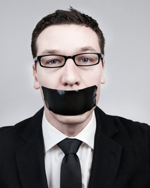 Photo of a man in suit with duct tape over his mouth