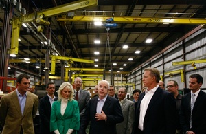 John McCain in warehouse with wife Cindy, flanked by others. John Elway is in foreground, right