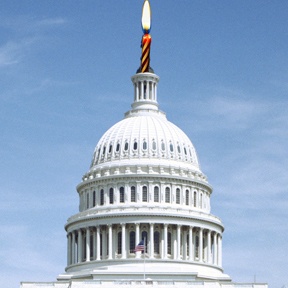 A picture of the Capitol building with a candle on top of the dome.