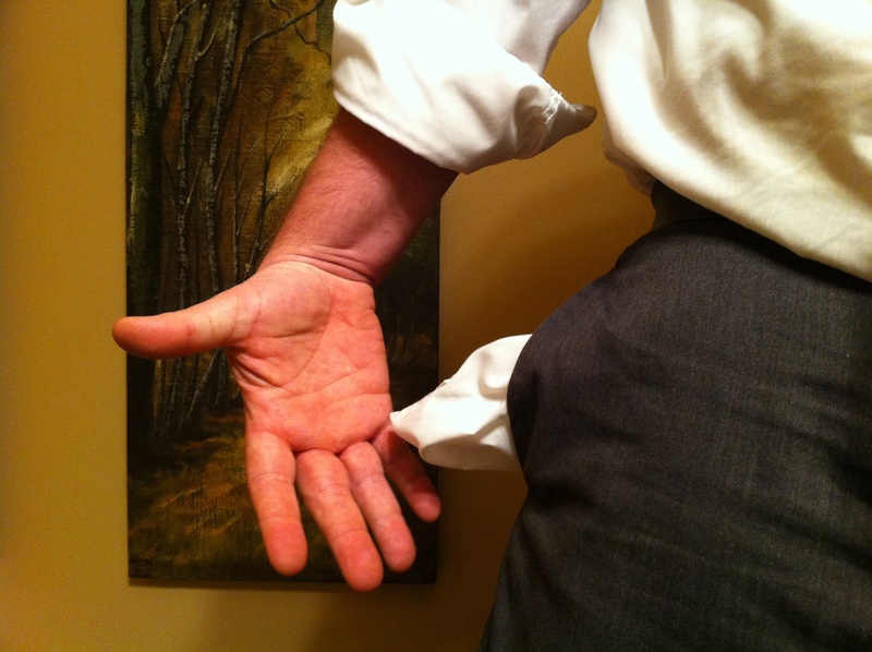 Image of a man's mid-torso with his hand pulling out the lining of an empty pocket from a dark pair of pants