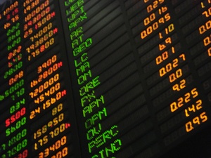 An electronic black board lit up with letters and numbers of stocks.