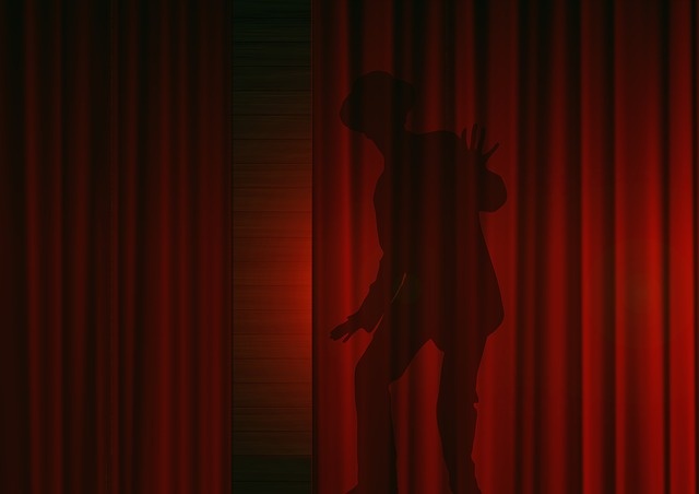 Silhouette of man behind red curtain