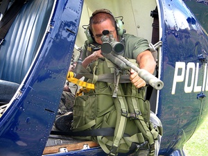 Sniper aims gun out of a police helicopter