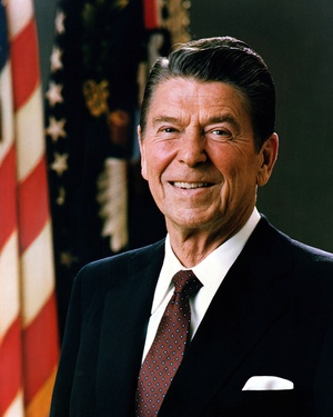Formal portrait of President Ronald Reagan in dark suit,dark red tie, with a U.S. flag in the background