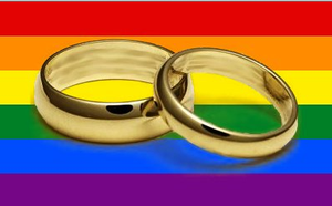 Two wedding rings in front of a rainbow banner