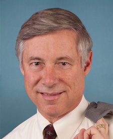 Head and shoulder shot of grey haired man with coat slung over his shoulder