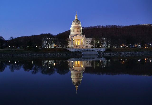 Photo of the domed West Virginia capitol building reflected in the Kanawha River at night