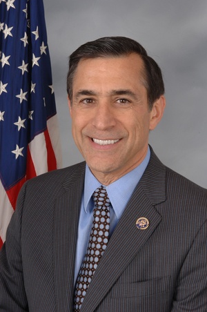 Darrell Issa with striped dark suit and polka dot tie in front of American flag