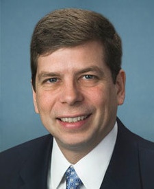 Head and shoulders shot of Sen. Mark Begich, brown-haired man in dark suit, white shirt and blue patterned tie