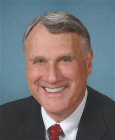 Head and shoulders shot of Jon Kyl, white male with greying hair in suitcoat and red tie