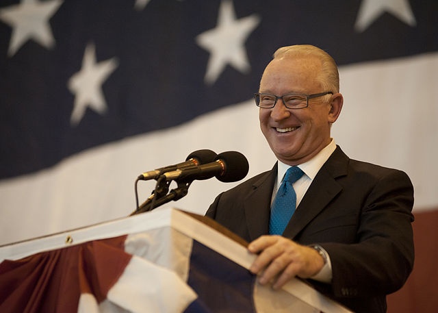Rep. Buck McKeon at lectern in front of an American flag wearing blue tie