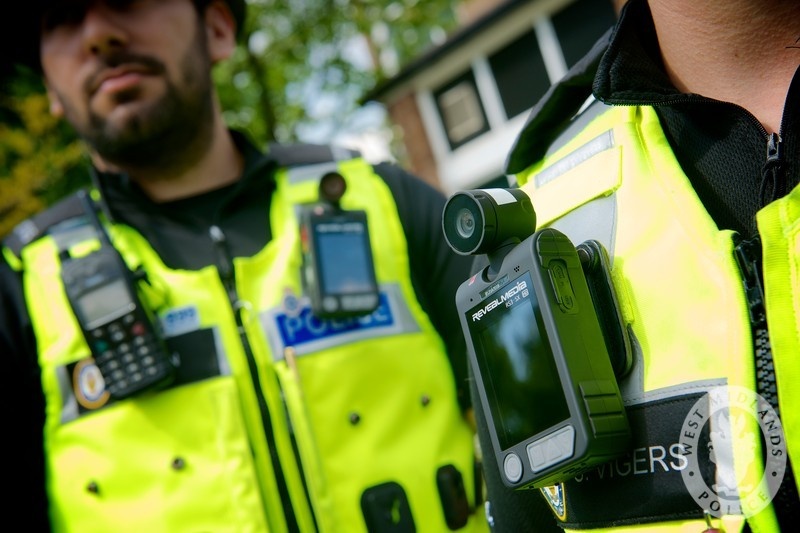 Police officers inn yellow vests model body worn camera.