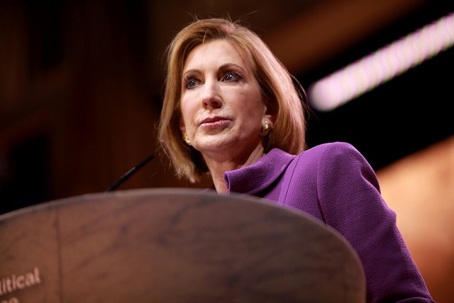 Carly Fiorina, in purple jacket, speaking before lectern