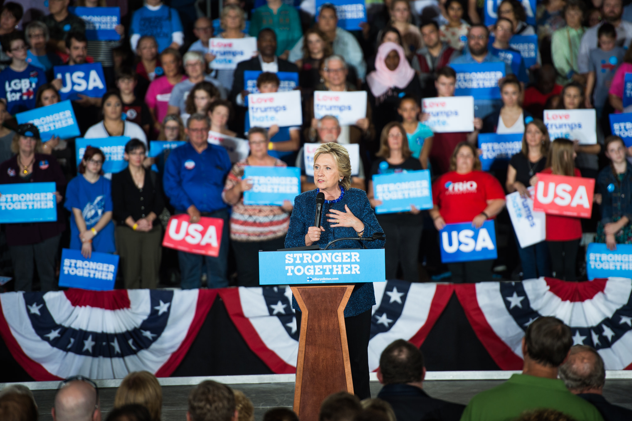 Hillary Clinton at a podium speaking at a rally.