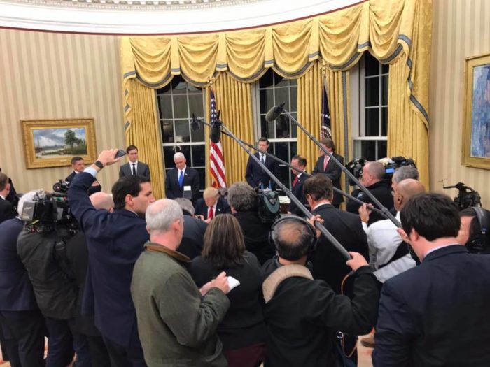 The press photographs President Trump signing documents in the Oval Office. [White House]