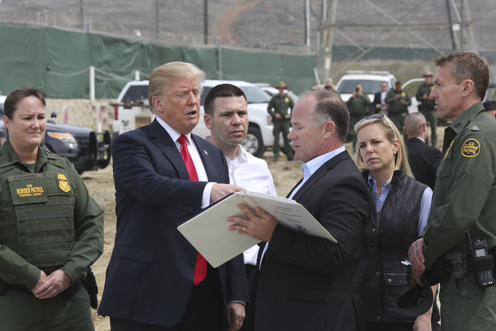 President Trump consults with Customs and Border Protection officials as he tours border wall prototypes. Image credit: CPB. 