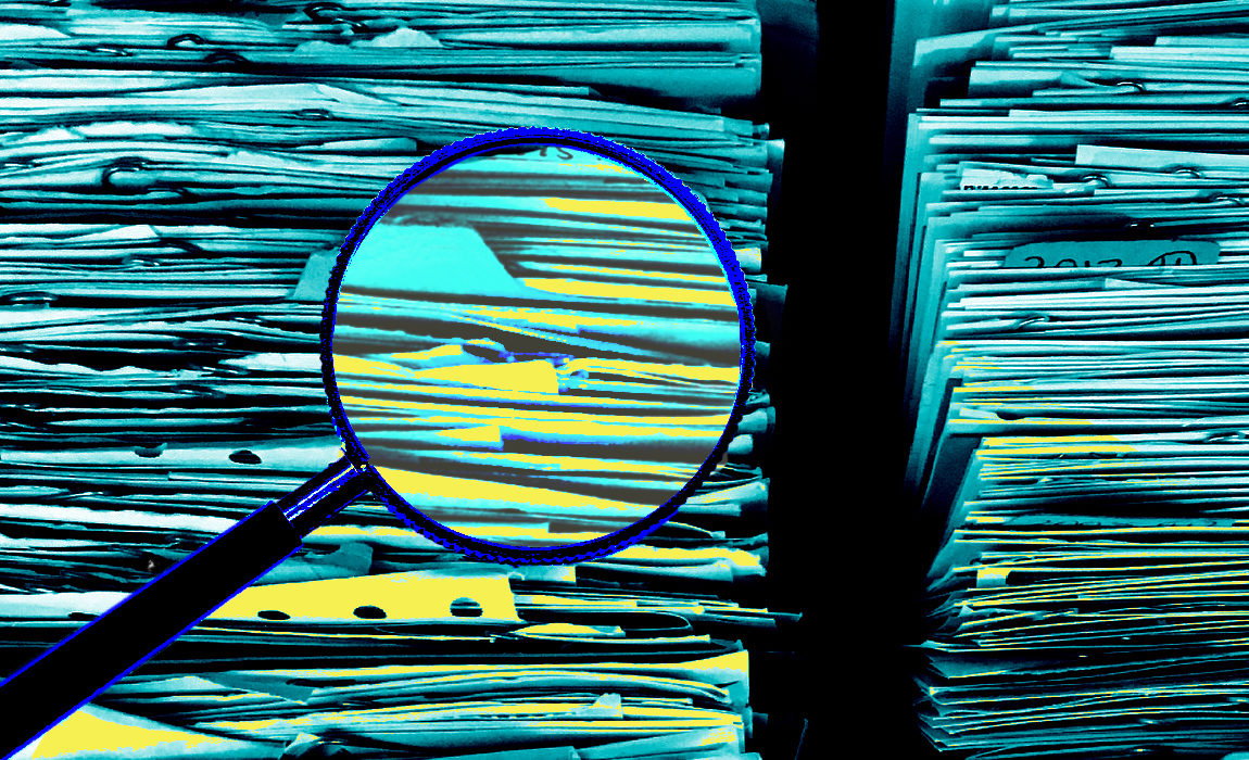 A magnifying glass over a stack of files. 